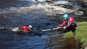 Trainee coach rescuing paddler with paddle.