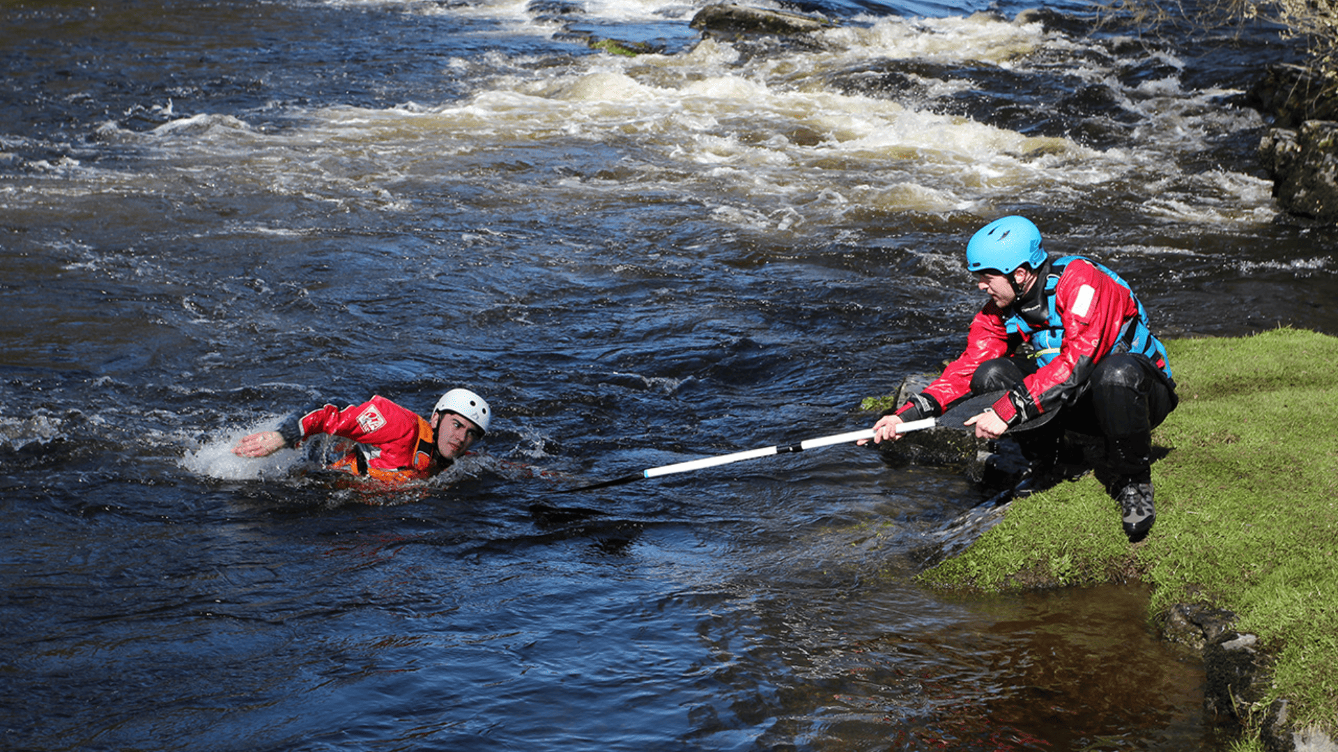 Trainee coach rescuing paddler with paddle.