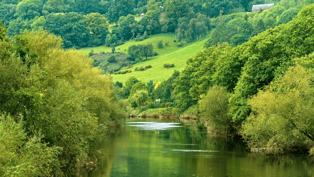 Stretch of river with green hills. Learn about Paddle UK waterways licences.