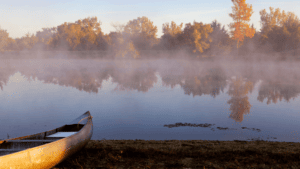 Canoe on shore by a misty lakeside. Introduction to Paddle UK.