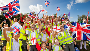 Spectators at an event. Children holding union flags in a crowd cheering on athletes.