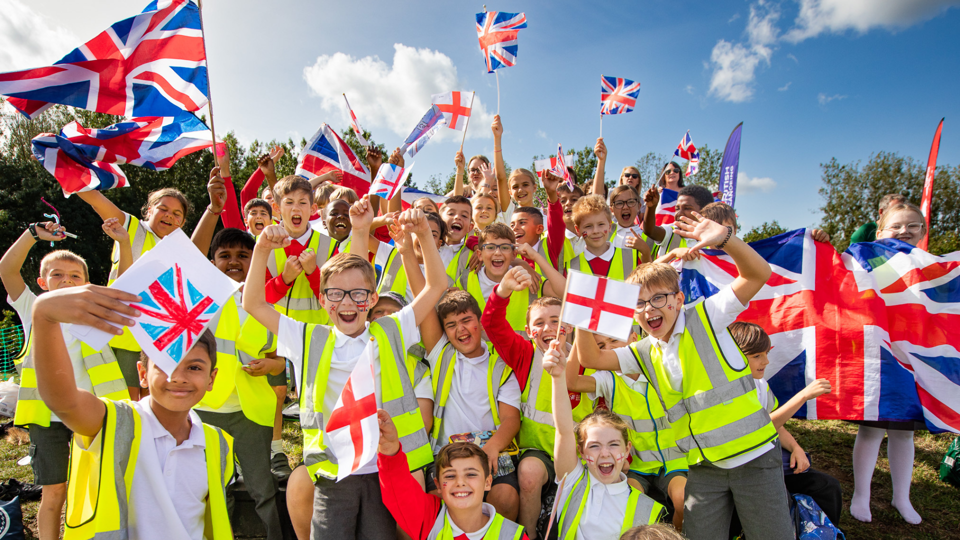 Spectators at an event. Children holding union flags in a crowd cheering on athletes.