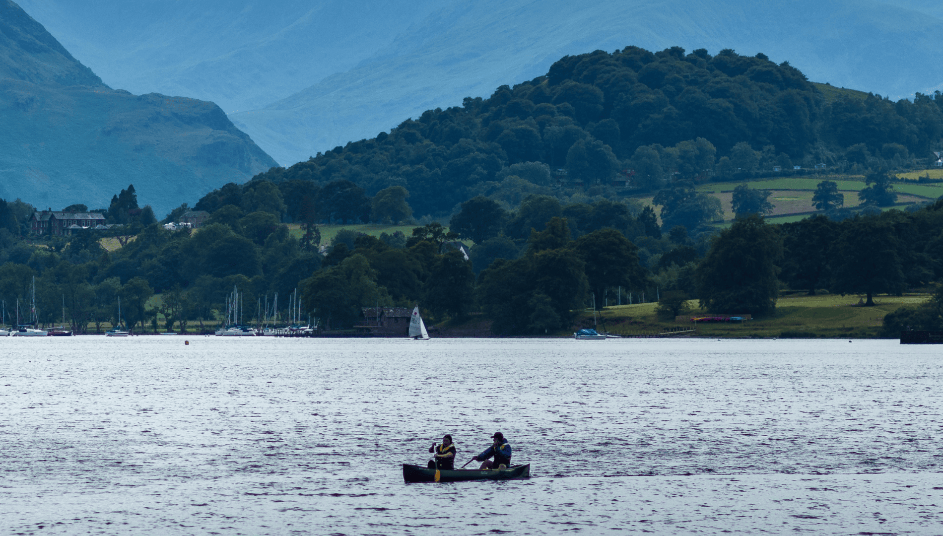 Ullswater with two people paddling a canoe. Used on safeguarding policies page.
