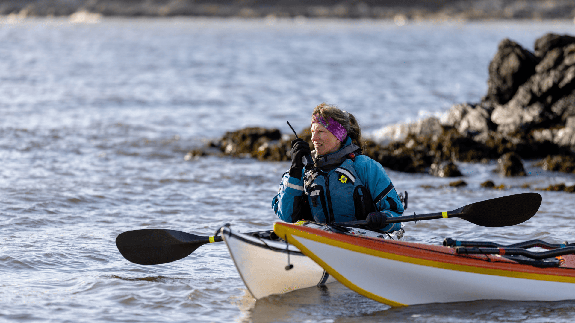 Online incident reporting. Female coach in a kayak with 2-way radio.
