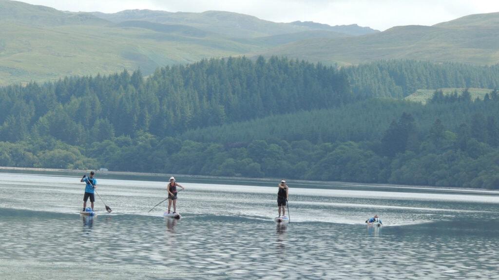 scenic view of Dean, Niall, Alison and Allistair paddling on stand up paddleboards on Loch Awe