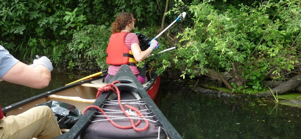 Woman cleaning up a river as part of the Big Paddle Cleanup.