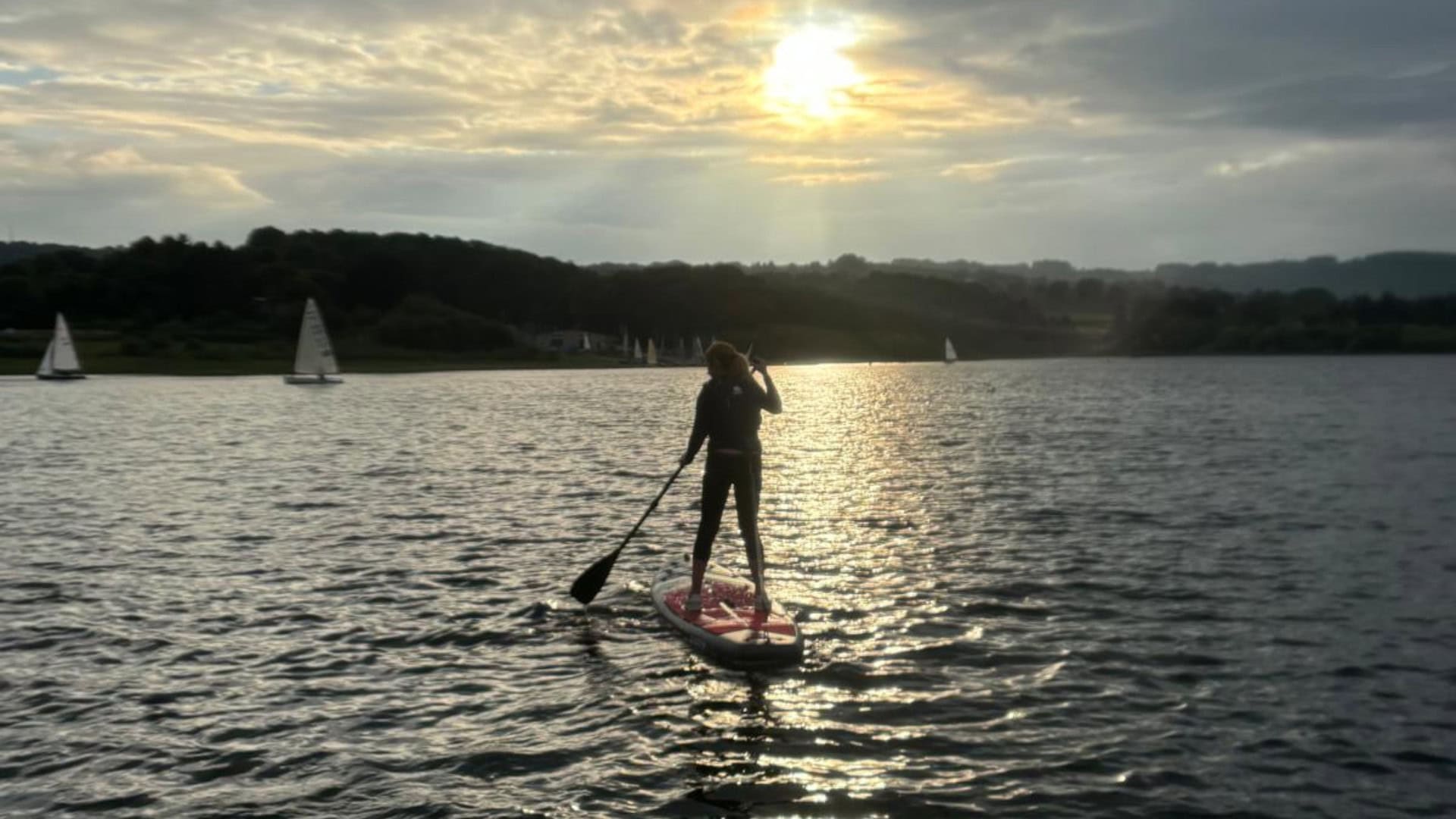 Kate Allatt paddleboarding at sunset on a lake