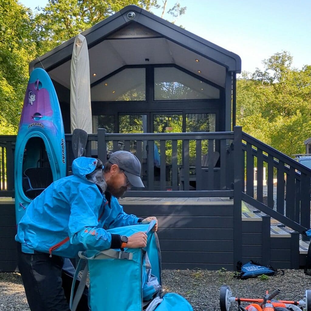 Man opens inflatable kayak outside glamping cabin