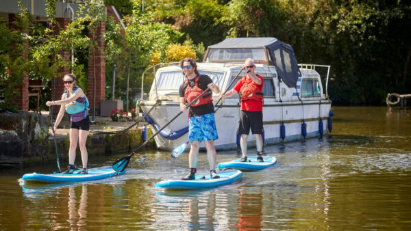 Three people paddleboarding. Become a member today.