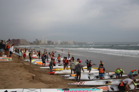 Paddlers waiting by the sea next to their surfskis.
