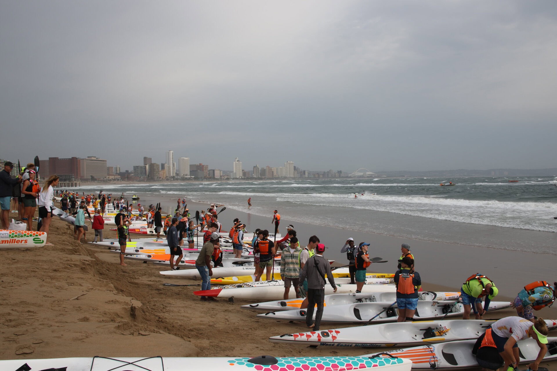 Paddlers waiting by the sea next to their surfskis.