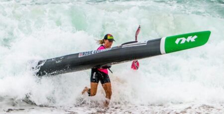 Rosie Edwards running out of the surf in Durban, South Africa carrying a surf-ski.
